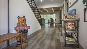 Eine Holzskulptur eines Bären mit einem Schild, einer Treppe, einem Essbereich und einem Bücherregal voller Bücher.