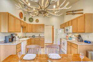 A kitchen with wooden cabinets, a central island, a chandelier, and a dining table set for two.
