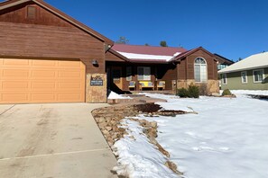 A two-story house with a garage, a stone foundation, and a snow-covered driveway. - Pet Friendly!  Fireplace, Fenced Yard, Mountain Views, Near Hot Springs (Pagosa Springs)