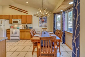 A kitchen with wooden cabinets, a stove, a microwave, and a dining table set for six. - Pet Friendly!  Fireplace, Fenced Yard, Mountain Views, Near Hot Springs (Pagosa Springs)