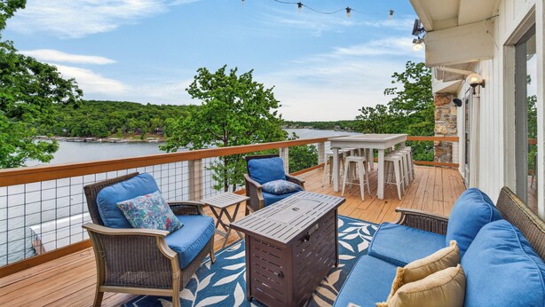 Une terrasse dotée de mobilier d’extérieur, d’une table et offrant une vue sur un lac.