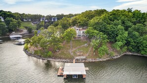 Une propriété au bord du lac, dotée d’un quai, d’une maison entourée d’arbres et d’un bateau.