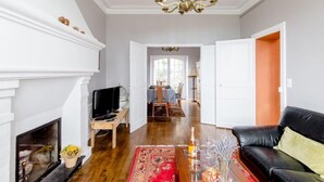 Ein Wohnzimmer mit Kamin, einem schwarzen Ledersofa, einem Fernseher und einem roten Teppich.