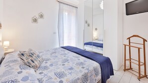 A bedroom with a bed, a wardrobe, a TV, and a wooden rack. - Casa Le Palme with an equipped outdoor area (Porto Azzurro)