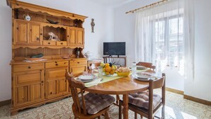 A dining area with a wooden cabinet, a television, and a window with sheer curtains. - Nice Apartment in Valtura With 2 Bedrooms (Liznjan)