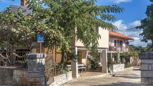 A residential building with a stone gate, a sign indicating 'APARTMAN DANA', and a balcony with potted plants. - Nice Apartment in Valtura With 2 Bedrooms (Liznjan)