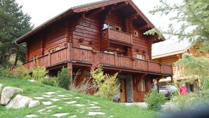 Une cabane en bois avec un balcon et des fondations en pierre.