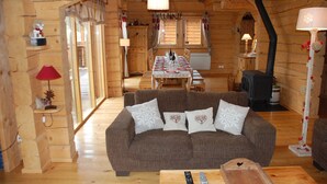 L’intérieur chaleureux d’un chalet en bois comprend un coin repas, un canapé agrémenté de coussins décoratifs et une cheminée.