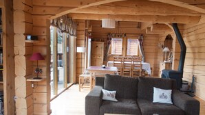 L’intérieur d’un chalet confortable, avec un canapé, une table à manger et une cheminée.