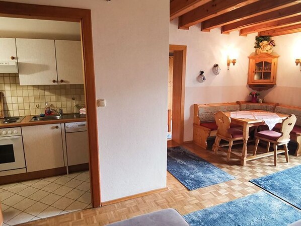 Une cuisine équipée de placards, d’un évier et d’une cuisinière. On y trouve également un coin repas avec une table et des chaises.