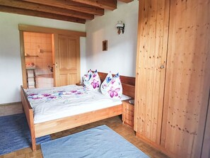 Une chambre à coucher avec un lit en bois, une table de chevet, une armoire et une porte donnant sur une autre pièce.