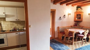 Una cocina con armarios, un lavamanos y una estufa. Hay un comedor con una mesa y sillas.