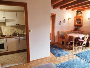 Una cocina con armarios, un lavamanos y una estufa. Hay un comedor con una mesa y sillas.