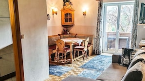 Una sala de estar con un sofá, una mesa de comedor con sillas, un aparador de madera y vistas a través de un ventanal.