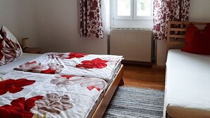 Una habitación con cama, sofá, ventana con cortinas y un radiador.