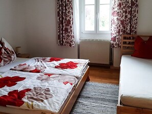 Una habitación con cama, sofá, ventana con cortinas y un radiador.