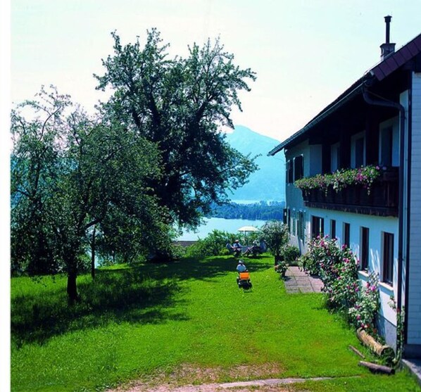 Una casa con césped, un árbol y vistas a un lago y montañas.