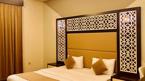 Ein Hotelzimmer mit einem großen Bett, einem Nachttisch, einem Schreibtisch und einer dekorativen Wandverkleidung.