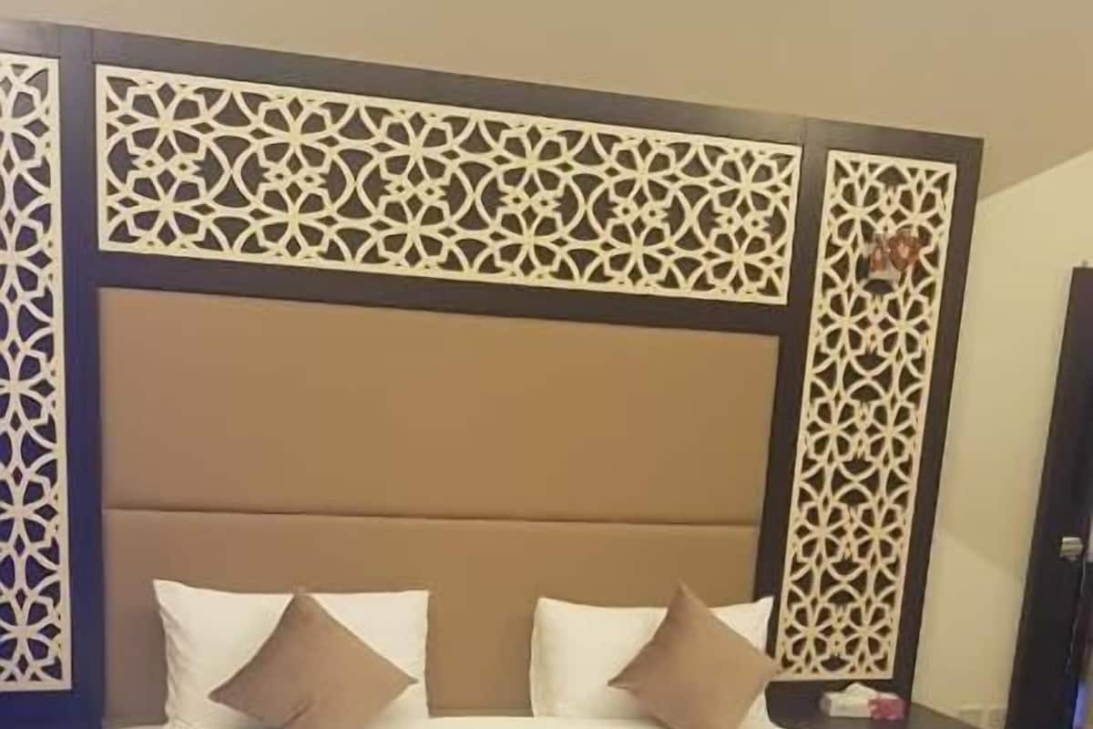 A neatly made bed with a headboard, pillows, and a blanket.