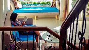 A person sitting on a sofa with a guitar leaning against the wall, reading a book. - Jolie House - Villa 2 Double Rooms - Great Getaway (Da Lat)