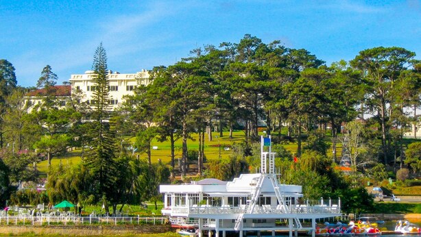 A white boat docked at a pier with a white building in the background. - Jolie House - Villa 2 Double Rooms - Great Getaway (Da Lat)