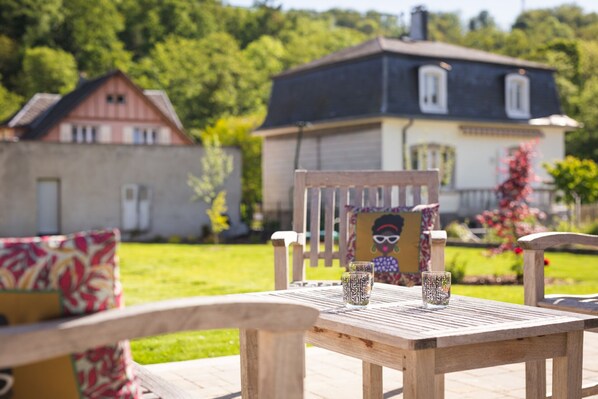 A wooden table with two glasses and a chair with a cushion.