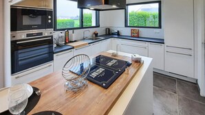 Una cocina moderna con horno empotrado, cafetera y un amplio ventanal.