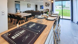 Un comedor moderno con una larga mesa de madera, individuales negros y vistas al exterior a través de grandes puertas correderas.