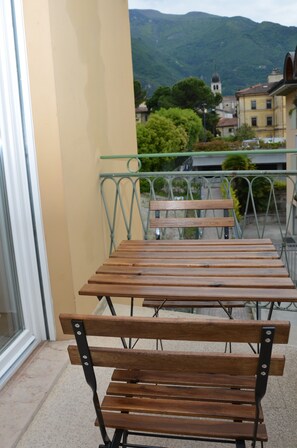 Un balcon doté de bancs en bois et d’une rambarde en métal, offrant une vue sur un paysage montagneux.