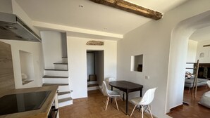 Une cuisine moderne avec un plan de travail en bois, un coin repas comprenant une table et des chaises, et un escalier menant à un autre niveau.