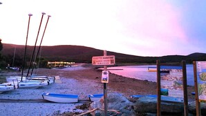 Une plage où plusieurs bateaux sont amarrés et où se trouve un panneau indiquant le service de navette maritime.