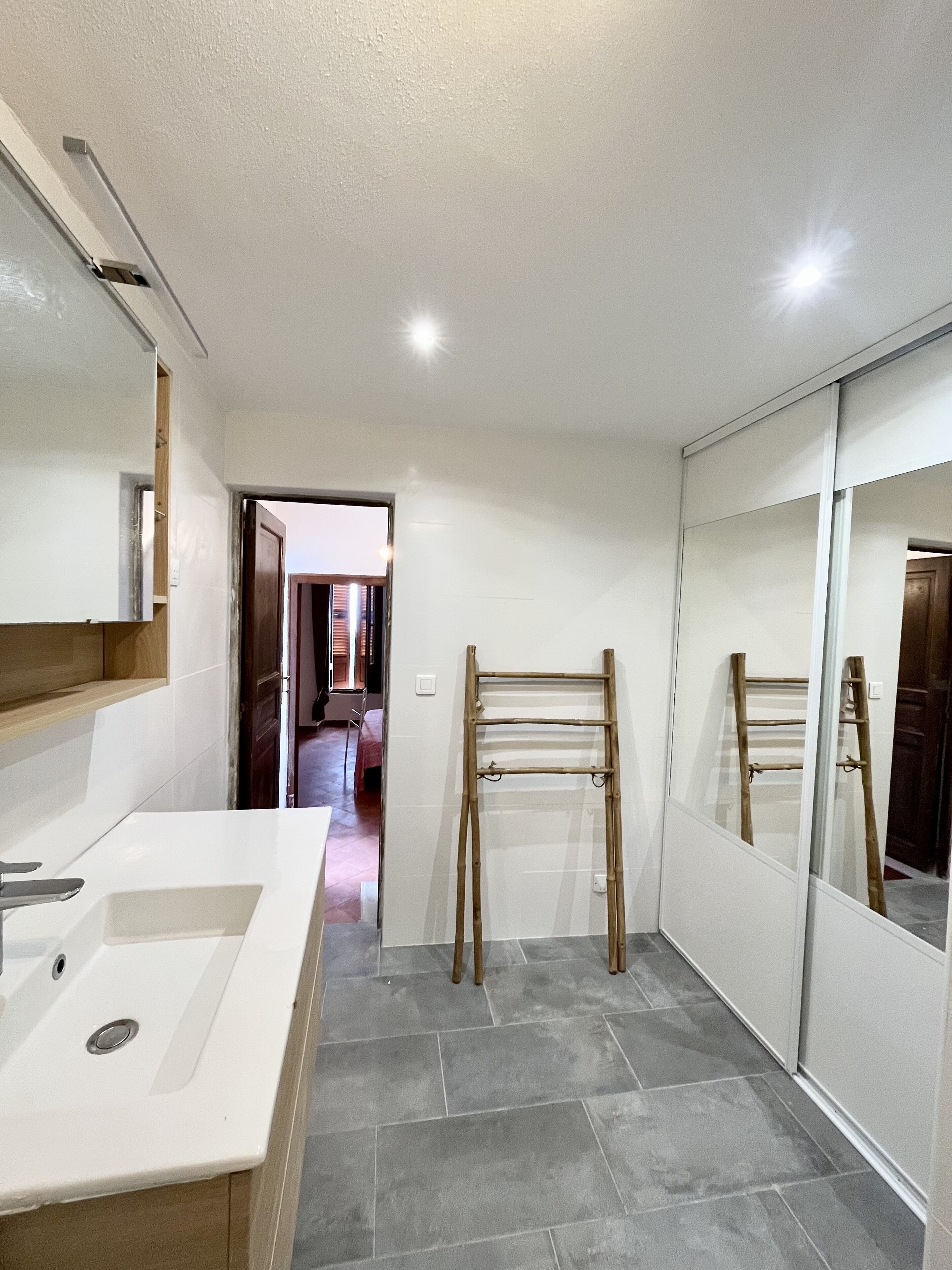 A modern bathroom with a large mirror, a sink, and a shower area.