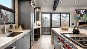 A modern kitchen with a large island, built-in appliances, and a view of a snowy landscape. - The Ontario | 5BR Epic Views, Heart of Park City (Park City)