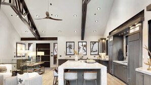 A modern kitchen with a large island, bar stools, and a ceiling fan. - The Ontario | 5BR Epic Views, Heart of Park City (Park City)