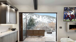 A modern kitchen with a large window, a fireplace, and a view of a snowy mountain. - The Ontario | 5BR Epic Views, Heart of Park City (Park City)