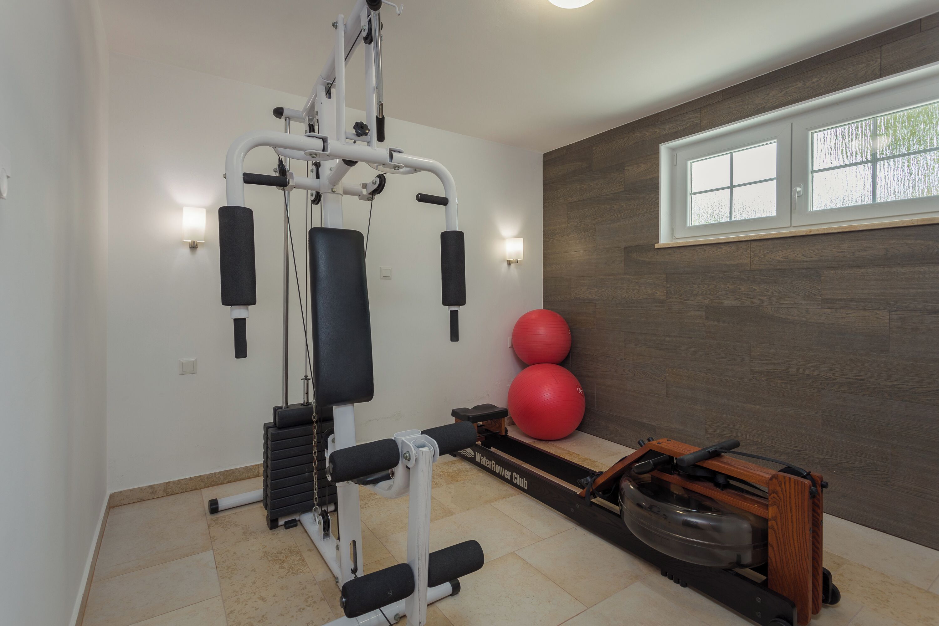 A home gym with a weight machine, exercise balls, and a rowing machine.