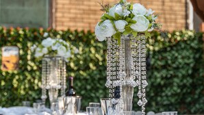 Mesa dispuesta para un evento al aire libre elegante, con mantel negro, platos blancos y copas de vidrio transparente.