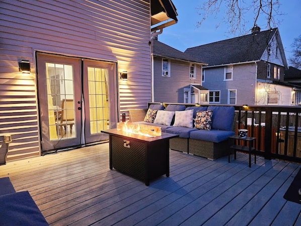 A deck with a fire pit, outdoor seating, and a sliding glass door leading to an interior room.