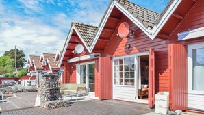 A row of red wooden cabins with white trim, each featuring a large window and a door.