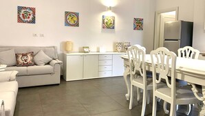 Una cocina moderna con armarios blancos, una mesa de comedor con sillas blancas y decoración en la pared.