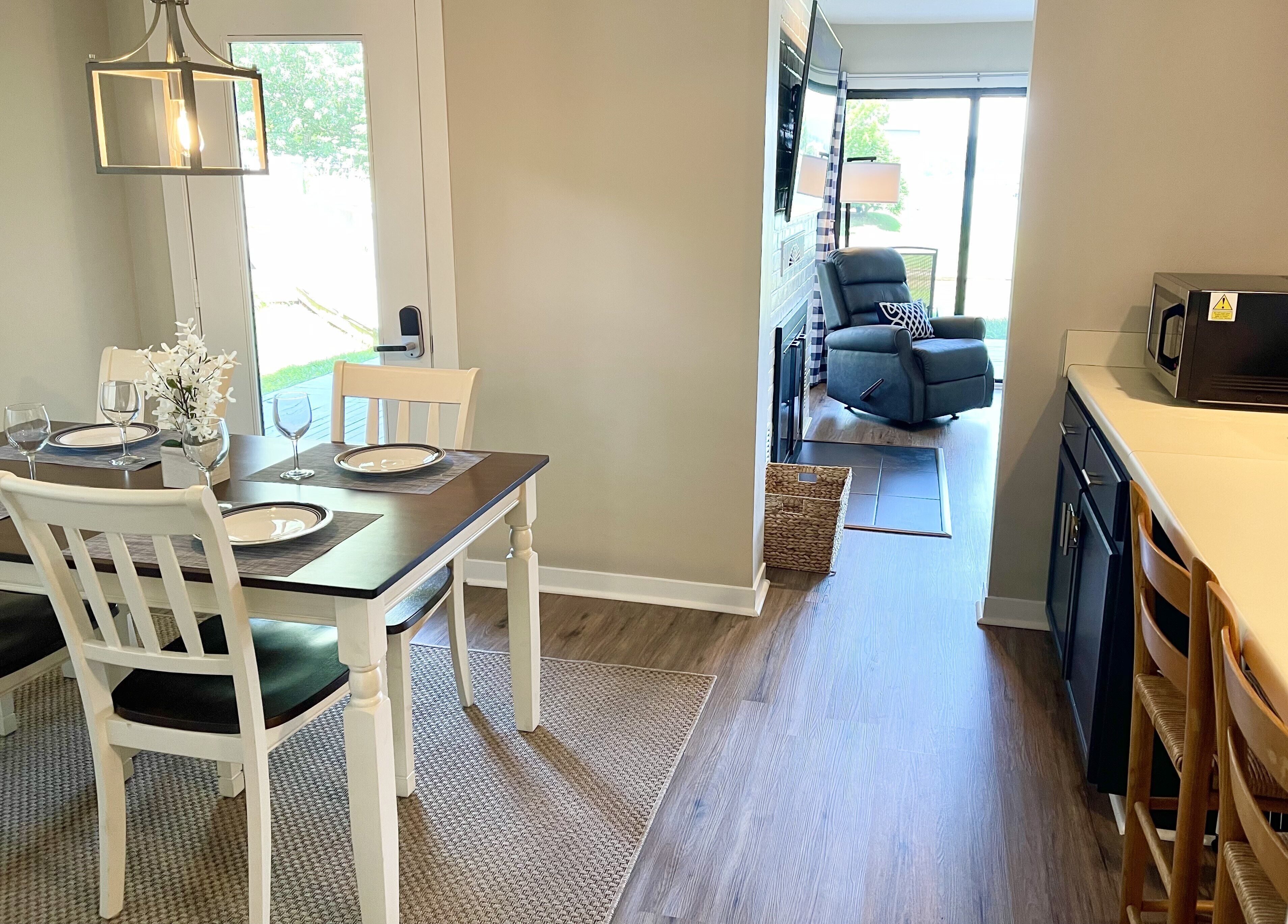 A dining area with a table set for four, a chair, and a hanging light fixture.