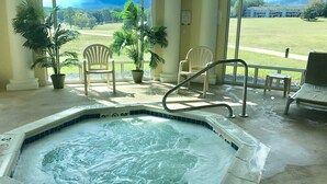 Un jacuzzi con vista a un campo cubierto de césped y un edificio al fondo.