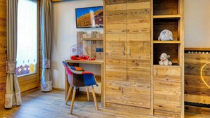 A cozy room with a wooden desk, a chair, a TV, and a wardrobe with shelves. - Aparment for holiday  (Livigno)
