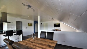 Een moderne keuken met witte kastjes, een houten eettafel en zwarte stoelen.