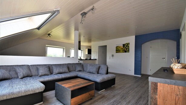 Een moderne woonkamer met een hoekbank, een salontafel en een houten decoratie.