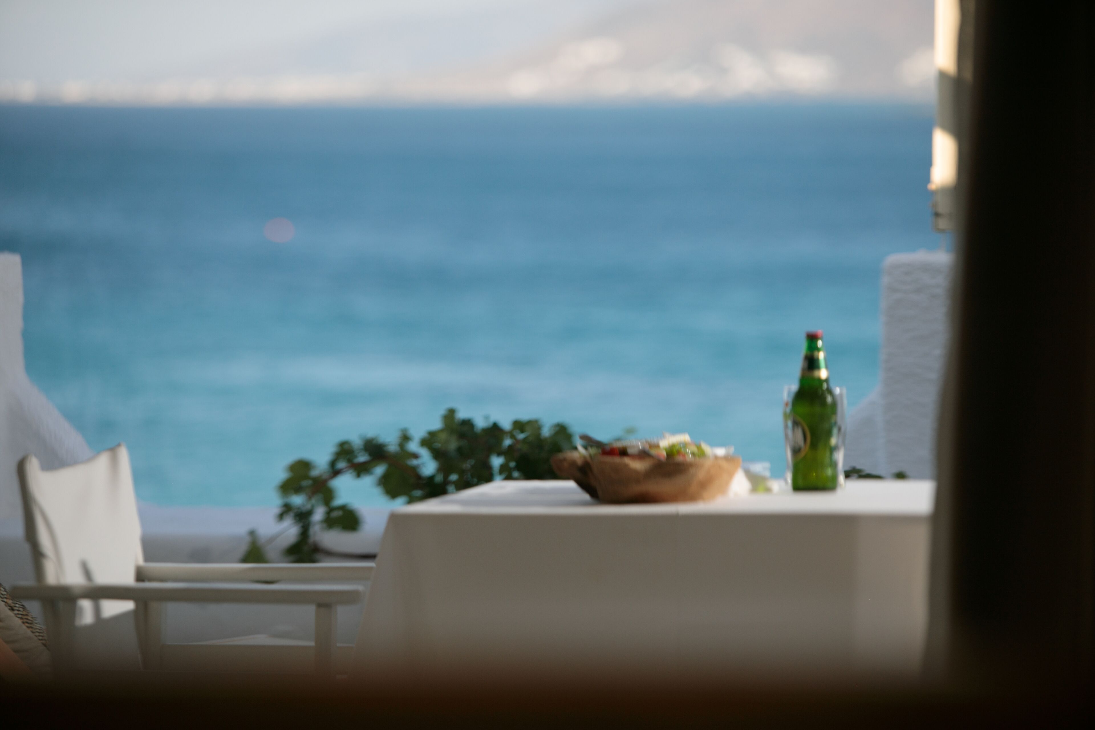 A table with a bowl of food and a bottle, overlooking a body of water.