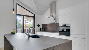 Una cocina moderna con una isla grande, horno empotrado y vistas al exterior.