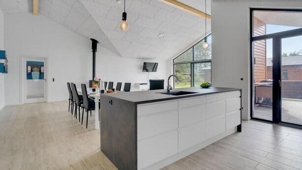 Una cocina moderna con una isla grande, un comedor con sillas y un televisor montado en la pared.