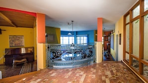 A hallway with a checkered floor, a piano, and a decorative railing.