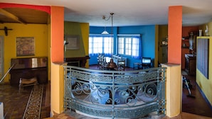 A spacious room with a central bar area, a piano, and a patterned floor.